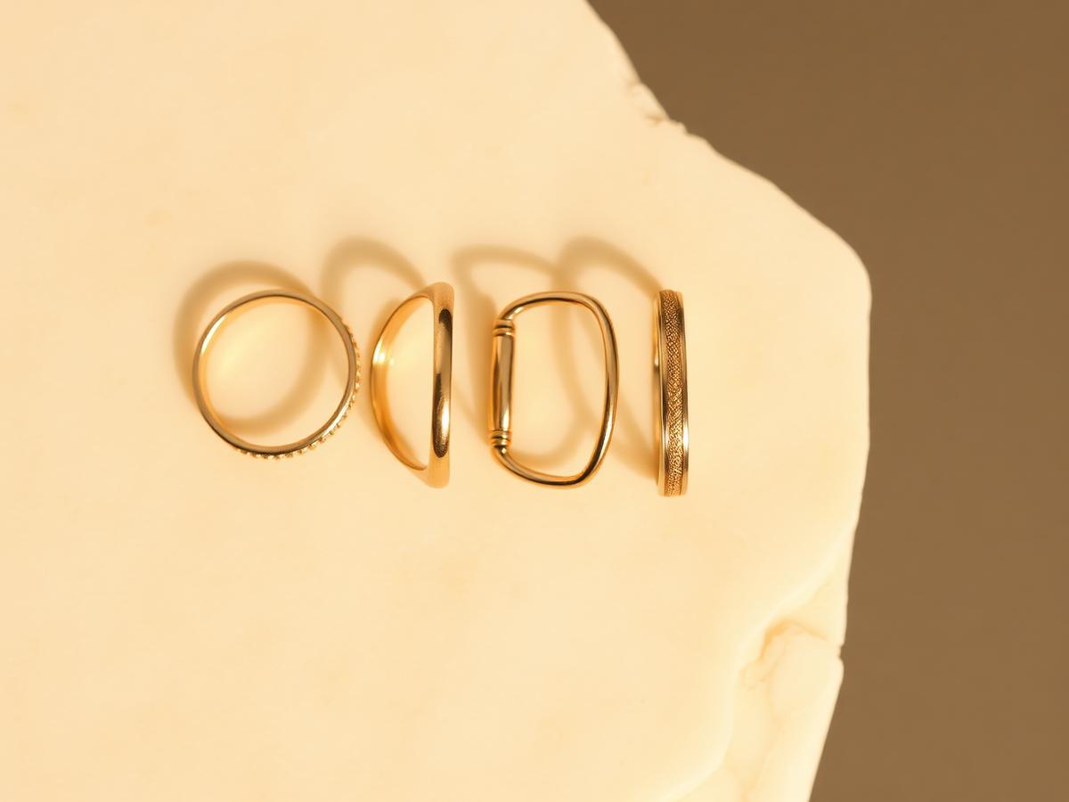 Four gold rings in different karats laid on ivory stone